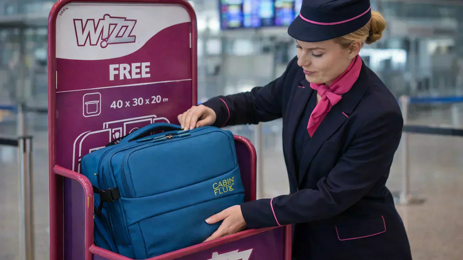 דיילת של חברת WIZZ AIR מודדת תיק עליה למטוס במתקן מדידה בשדה התעופה