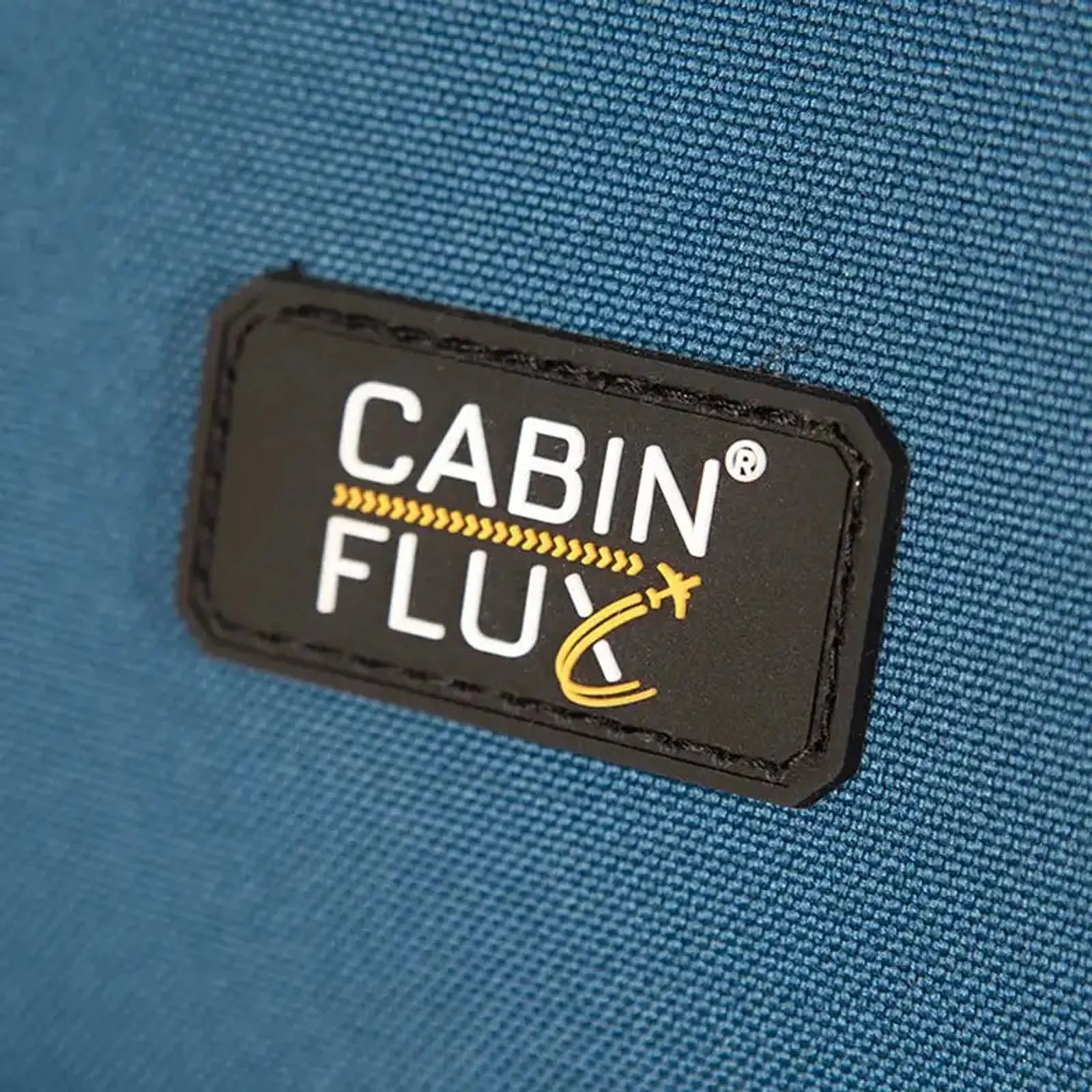תווית מותג CABIN FLUX במזוודה גדולה Spirit C-Lite שלדת קרבון, בד Eva Composite עמיד לשחיקה, תקריב
