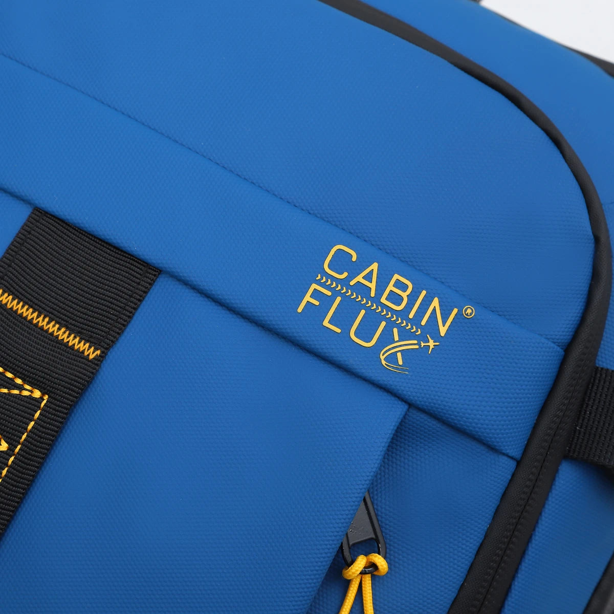 תקריב לוגו זהוב CABIN FLUX רקום על בד Ballistic Nylon כחול של תיק עלייה למטוס דגם Apex Ranger