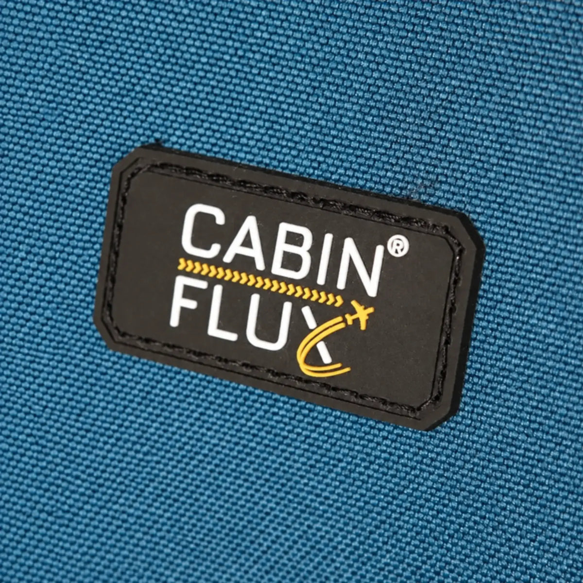 תקריב תווית לוגו CABIN FLUX על מזוודת Spirit C-Lite בצבע כחול, בד Eva Composite Fabric רב-שכבתי עמיד לשחיקה ודוחה מים