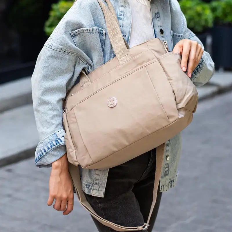 תיק צד COOLPASE דגם Carry Travel Tote בצבע חאקי נישא ברחוב בזמן נסיעה יומיומית, עיצוב אלגנטי ונוח