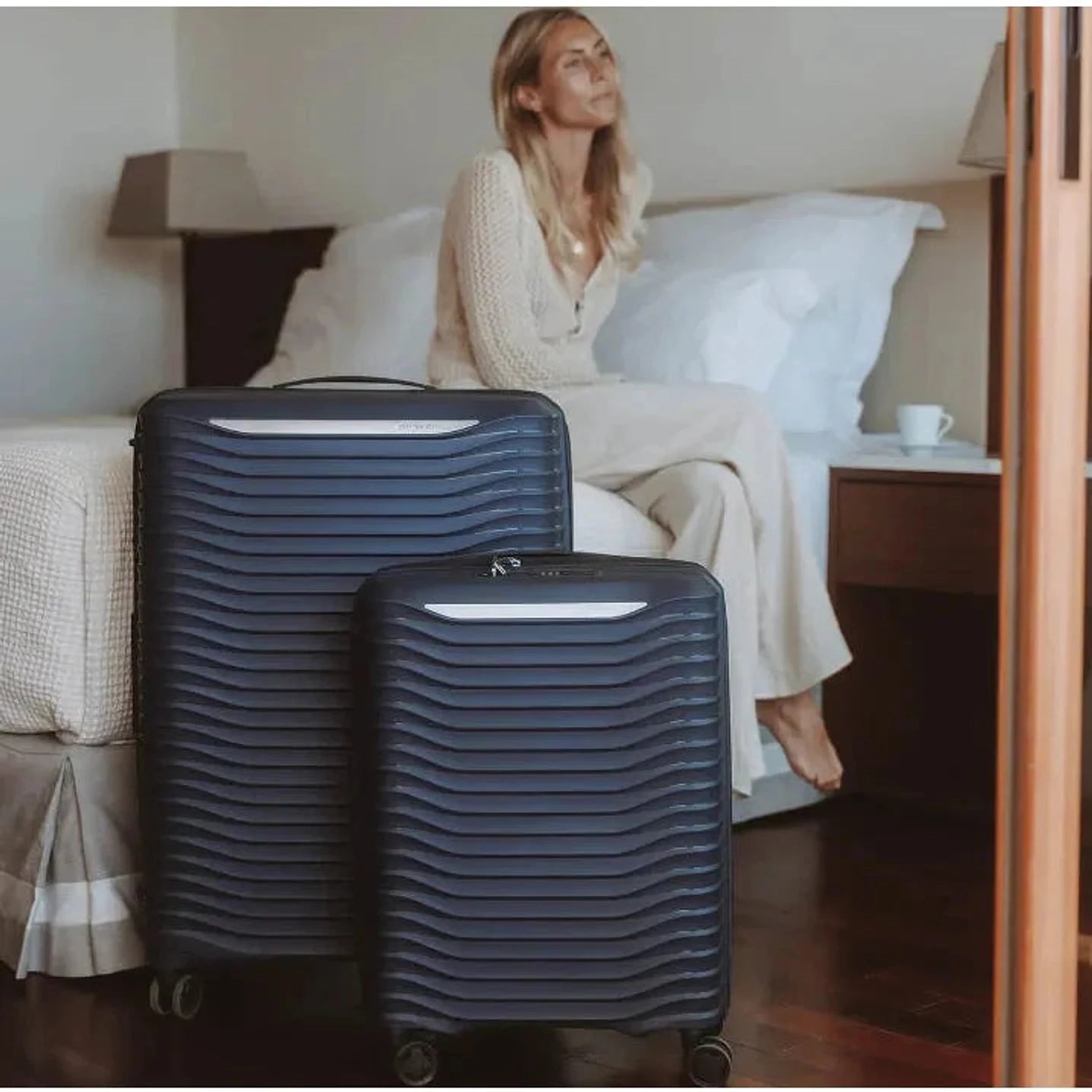 מזוודות קשיחות Samsonite Upscape בצבע נייבי בחדר מלון - עיצוב גלי ייחודי, מיוצרות במפעלי סמסונייט אירופה