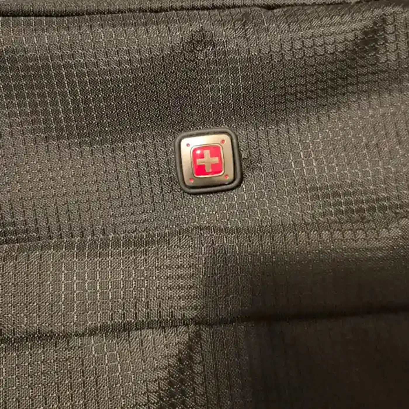 מזוודת בד SWISS מתקפלת עליה למטוס, תקריב על לוגו סוויס מקורי על בד ריסטופ איכותי