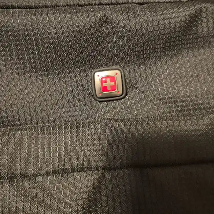 מזוודת בד SWISS מתקפלת עליה למטוס, תקריב על לוגו סוויס מקורי על בד ריסטופ איכותי