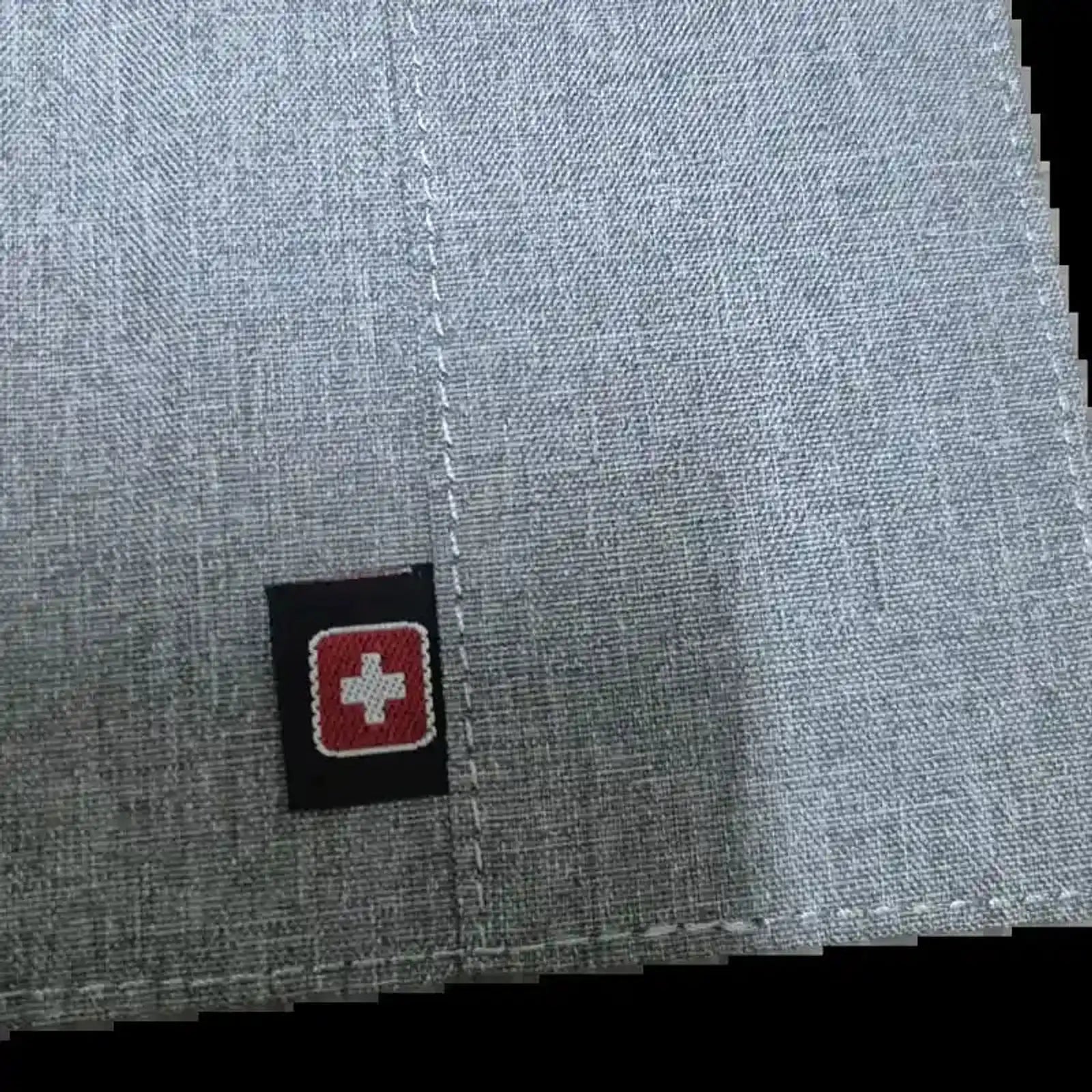 תקריב על לוגו SWISS האדום המובלט בכיסוי הדרכון Geneva, מעטפת EVA קשיחה בצבע אפור בהיר