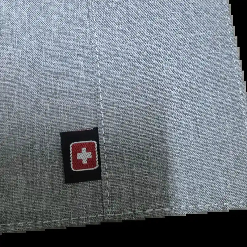 תקריב על לוגו SWISS האדום המובלט בכיסוי הדרכון Geneva, מעטפת EVA קשיחה בצבע אפור בהיר