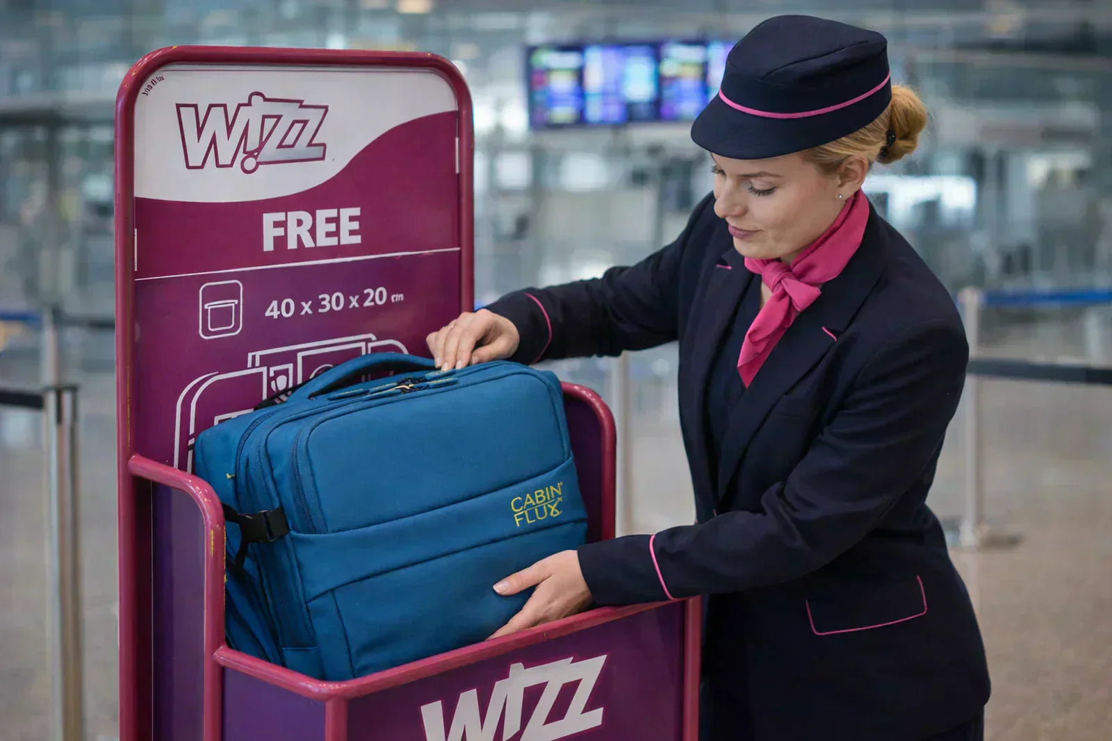 דיילת של חברת WIZZ AIR מודדת תיק עליה למטוס במתקן מדידה בשדה התעופה