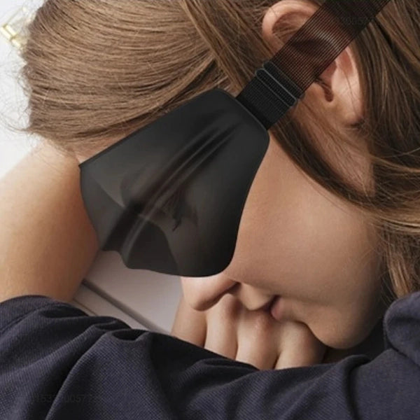אישה ישנה על הצד עם מסכת עיניים 4D שחורה של Dreamlight בטיסה, ממחישה חסימת אור מלאה ונוחות בשינה
