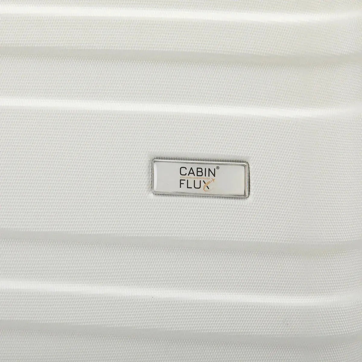 לוחית המותג CABIN FLUX על מזוודת Celine בצבע שמנת לבן, מבט קרוב על הלוגו המתכתי ועל מעטפת ה-ABS הקשיחה והעמידה