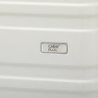 לוחית המותג CABIN FLUX על מזוודת Celine בצבע שמנת לבן, מבט קרוב על הלוגו המתכתי ועל מעטפת ה-ABS הקשיחה והעמידה