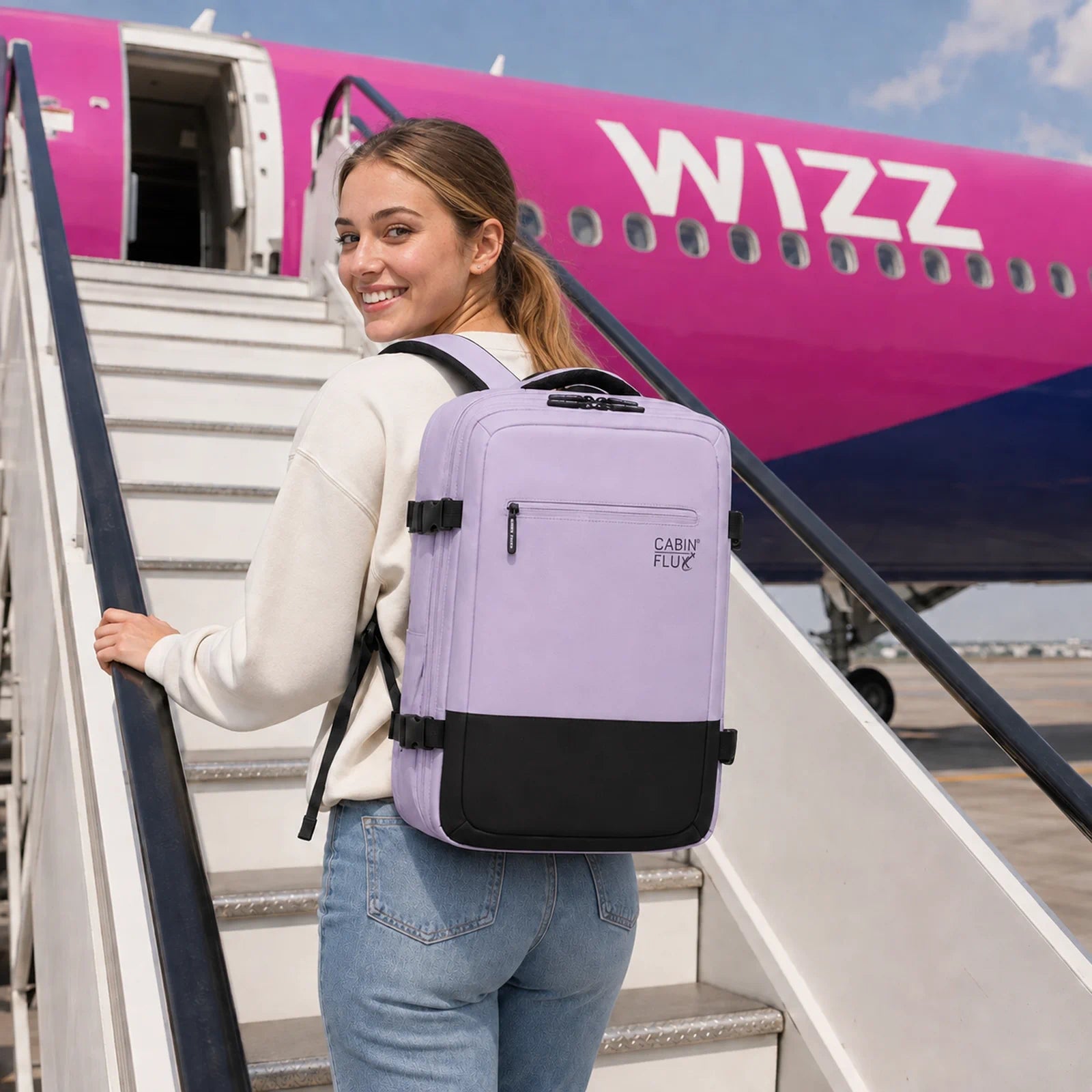 צעירה עולה למטוס WIZZ עם תיק גב עליה למטוס בצבע לילך CABIN FLUX ICONIC Soft Tones