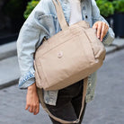 תיק צד COOLPASE דגם Carry Travel Tote בצבע חאקי נישא ברחוב בזמן נסיעה יומיומית, עיצוב אלגנטי ונוח