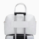 תיק נסיעות Kate Hill Bloom Overnight Tote מולבש על ידית טרולי מזוודה באמצעות שרוול אחורי, בצבע לבן