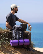 תיק טיולים Outdoor Revolution Cygni 45L בצבע כחול בסצנת שטח מול הים, עם רצועות חיצוניות לקשירת ציוד נוסף