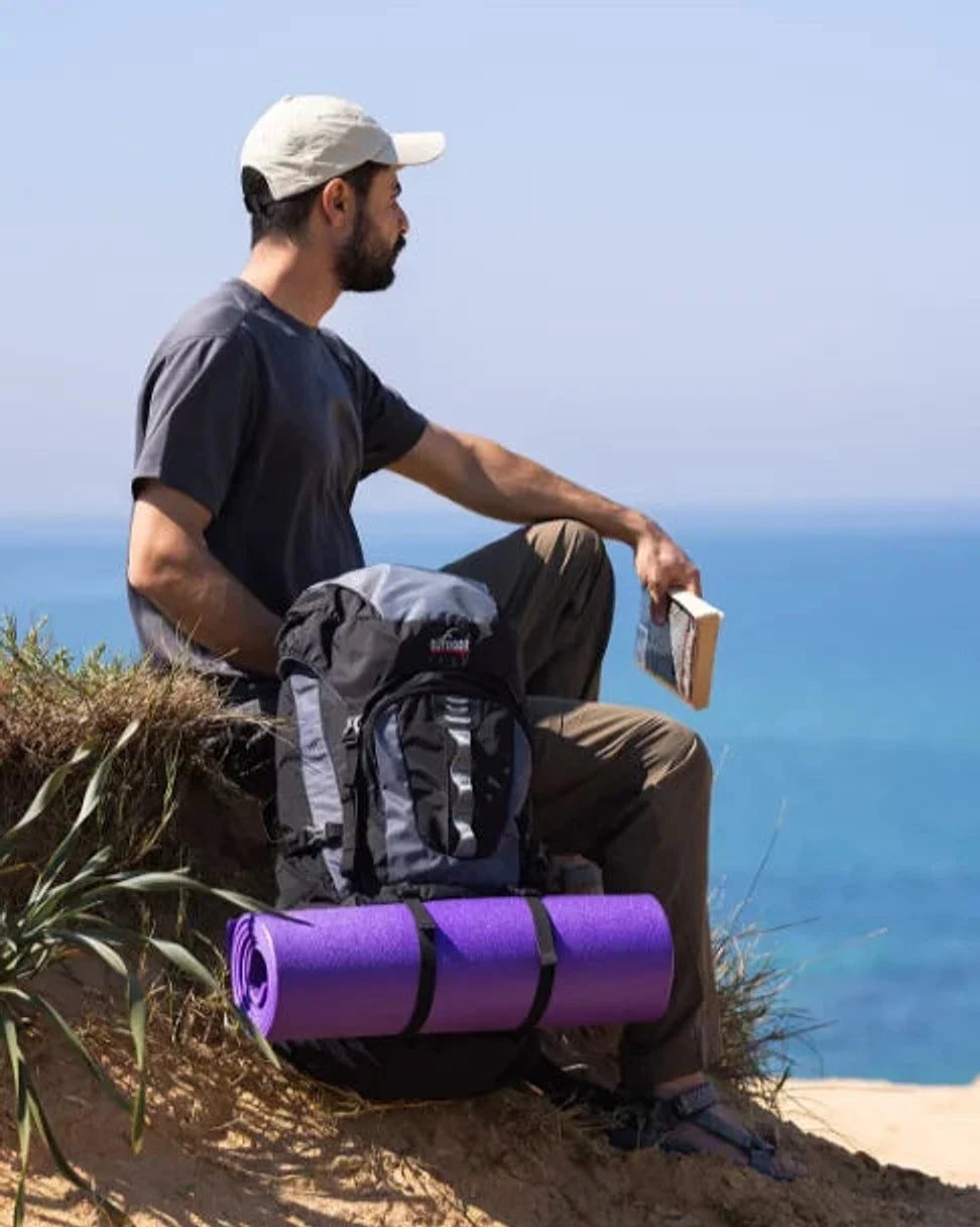 תיק טיולים Outdoor Revolution Cygni 45L בצבע כחול בסצנת שטח מול הים, עם רצועות חיצוניות לקשירת ציוד נוסף