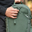 תקריב ידית הנשיאה העליונה של תרמיל יום Outdoor Revolution Fuji 24 בצבע ירוק, יד אוחזת בידית בזמן טיול יום