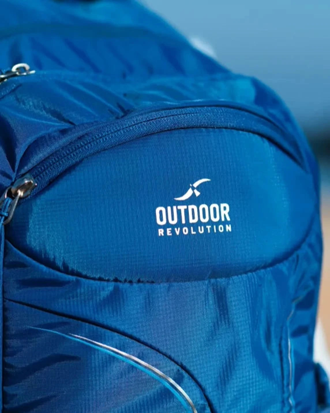 תרמיל יום Outdoor Revolution Makalu 28 ליטר בצבע כחול, תקריב על לוגו המותג הרקום על תא קדמי בבד פוליאסטר
