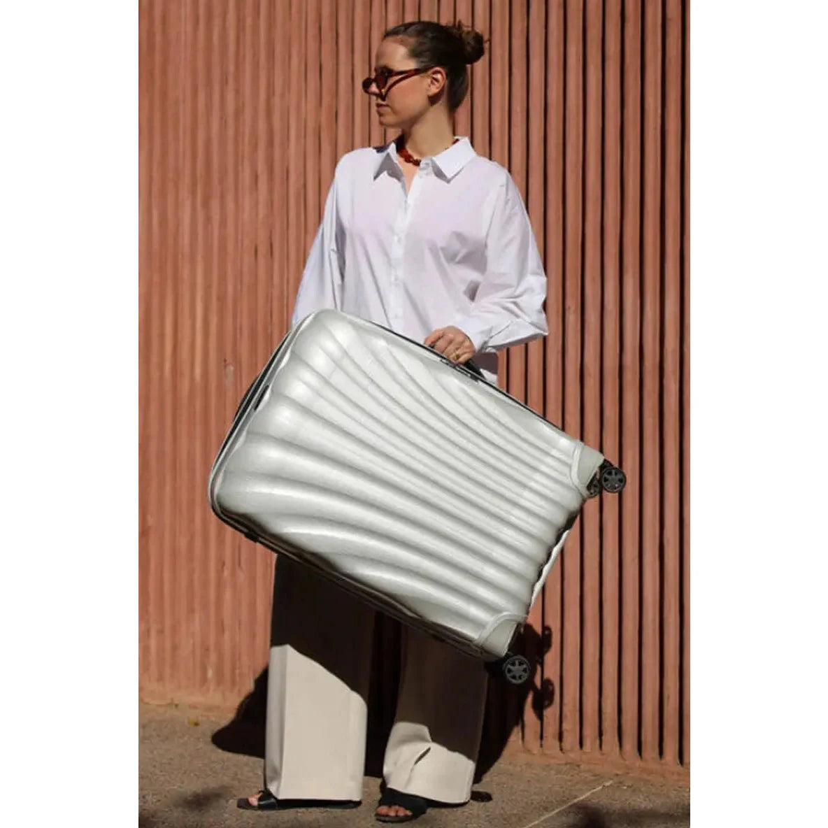 מזוודה קשיחה Samsonite C-lite Spinner במשקל 2.8 ק"ג בלבד, הדגמת נשיאה קלה ביד אחת בסצנת נסיעות