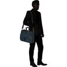 תיק צד עסקי Samsonite Urban Eye בצבע נייבי בנשיאה על כתף איש עסקים, מבט מצב שימוש יומיומי במשרד ובנסיעות