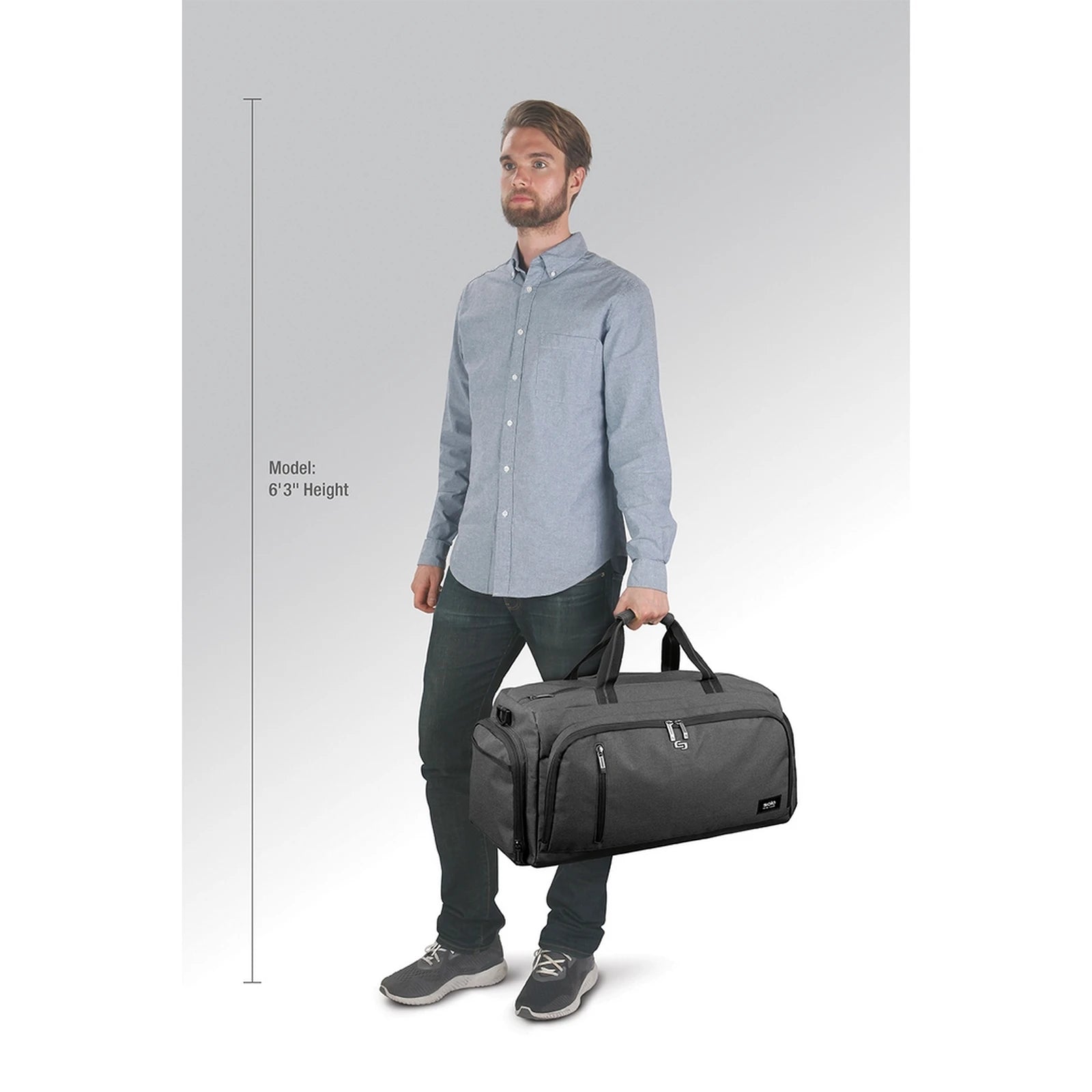 המחשת גודל: תיק דאפל SOLO New York דגם Highline 54 ליטר בצבע אפור נישא ביד לצד דוגמן בגובה 1.90 מטר