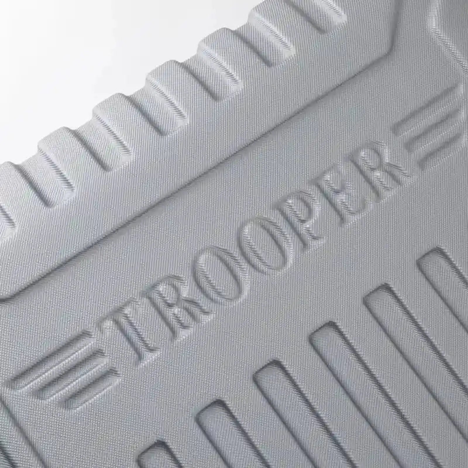 תקריב על לוגו TROOPER בחומר ABS מובלט על גוף המזוודה הקשיחה, מראה מרקם ייחודי ועיצוב קלאסי