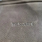 תקריב לוגו TRUSSARDI חרוט על עור ברידג' איטלקי איכותי, מראה מרקם העור האמיתי והתפר המוקפד של התיק