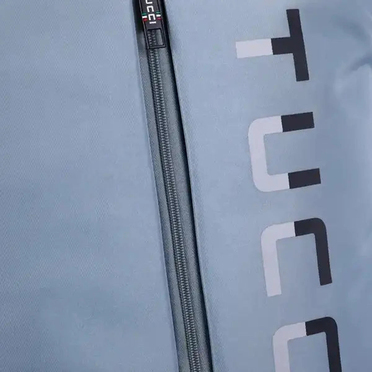 תקריב רוכסן מזוודת בד TUCCI LEGGERO אפורה בהירה עם דגל איטלקי ולוגו TUCCI בולט על הבד האוקספורד
