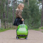 ילדה גוררת מזוודת ילדים קשיחה ZOOLITTLE DINO ירוקה ביער, ידית טרולי נשלפת וגלגלי סיליקון